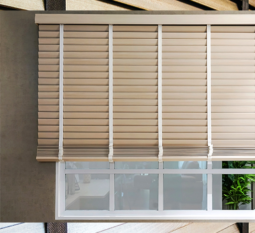 Beige window blinds partially open, showing a glimpse of a white-framed window and plant.